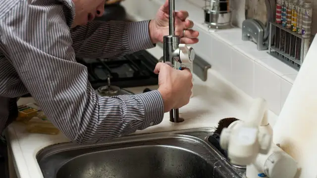 Plumber repairing a kitchen faucet
